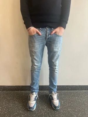 Dondup george - Säljer ett par ljusblå jeans från Dondup med klassisk femficksdesign och unika detaljer på bakfickan. Jeansen har en avslappnad passform och är tillverkade i slitstarkt denimtyg. Perfekta för en casual look och lätta att matcha med olika stilar