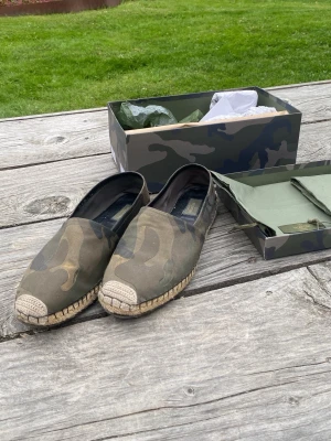 Valentino Espadrilles i camo - Säljer ett par Valentino Espadrilles i storleken 42! Säljs i befintligt skick, skorna har en skråma på undersulorna. Allt i bilden medföljs eftersom de kom med skorna, Boxen, 2 dustbags, farfetch tagg och annat. Nypriset ligger på runt 4-5 tusen. Skriv gärna vid frågor eller funderingar så hör jag av mig! In o köp👌👌   (Först till kvarn: 1549kr vid en snabb och smidig affär.)