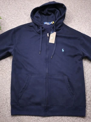 Mörkblå Polo Ralph Lauren zip up/ kofta - Snygg mörkblå hoodie från Polo Ralph Lauren med dragkedja och huva med snörning. Den är I storlek M kan även passa S. Tillverkad i 100% mjuk bomull. Vid snabbaffär kan priset diskuteras och även frakta vid det första tillfället.
