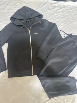 Hugo Boss - Hej Hugo Boss Tracksuit till salu. Den är i väldigt fin skick och är använd endast 2 gånger. Tröjan i storlek S och byxorna i M. Hör av er vid intresse!!