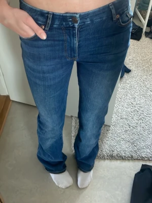 Blå bootcut jeans med klassisk look - Säljer ett par blå bootcut jeans med klassisk femficksdesign och snygga kontrastsömmar. Jeansen har en normal midja och är tillverkade i denim med lätt stretch för skön passform. Perfekt för dig som gillar en tidlös och avslappnad stil. Är tillräckligt långa för mig som är 177!