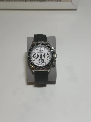 Seiko kronograf Panda mod - Seiko kronograf "Panda" stil mod Säljer en otroligt stilig och passande Seiko Panda mod. -Klockan har safirglas -Armbandet är av gummi, längden kan justeras -Klockan har tre subdials - Boettens diameter 40mml Vid frågor hör av dig! - Tim och minut visaren är quartz - sekund visaren är kronograff.
