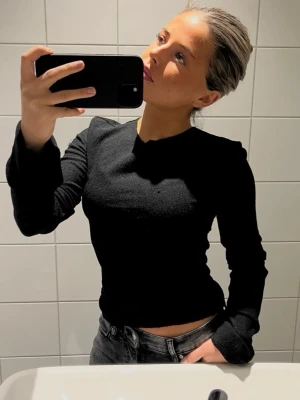 Svart långärmad topp - ADSGN STRL M - Säljer en svart ribbad långärmad topp med figurnära passform (liten i storlek). Toppen har rund halsringning och är tillverkad i ett stretchigt material som sitter snyggt på kroppen. Perfekt att styla med jeans eller kjol för en clean look. Storlek M men passar mig som är en XS
