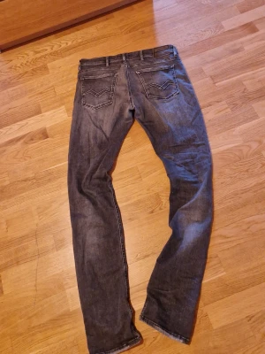 Replay jeans - Snygga mörkgrå slim fit jeans med klassisk femficksdesign och diskreta slitningar. Jeansen har raka ben och normal midja, perfekta för en avslappnad men stilren look. Tillverkade i mjukt denimtyg med lätt stretch för extra komfort.