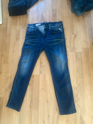 Replay Anbass slim fit jeans blå - Snygga blå slim fit jeans från Replay, modell Anbass. Jeansen har klassisk femficksdesign, lätt slitna detaljer och är tillverkade i stretchigt material för extra komfort. Perfekta för dig som gillar en smalare passform och stilren look.