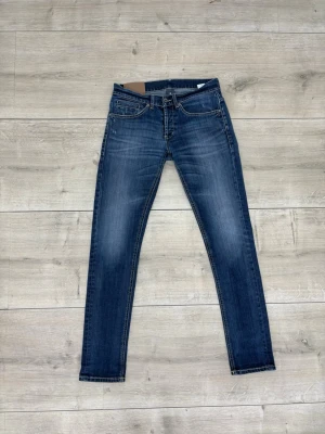Dondup slim fit jeans med slitningar - Snygga blå Dondup slim fit jeans med lätt slitna detaljer och klassisk femficksdesign. Jeansen har en smal passform och normal midja, perfekt för en trendig och avslappnad look. Materialet är stretchigt denim som ger bra komfort hela dagen. Hör av er vid frågor! 
