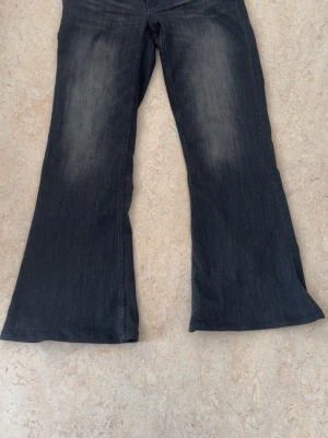Svarta bootcut jeans med slitningar - Snygga svarta bootcut jeans med lätt slitna detaljer framtill och bak. Jeansen har en klassisk femficksmodell och utsvängda ben.