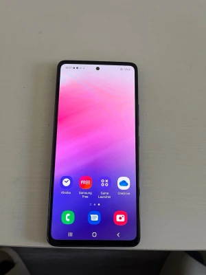 Samsung Galaxy svart Android-telefon - Snygg Samsung Galaxy med stor skärm och tunn svart design. Telefonen har rundade hörn, knappar på sidan och en modern look. Perfekt för appar, spel och sociala medier. Android-system och tydlig display gör den enkel att använda. Det som finns på baksidan av telefonen den var en gammal sticers som min lillebror hade klistrat på, går bort enkelt med lite alkohol.