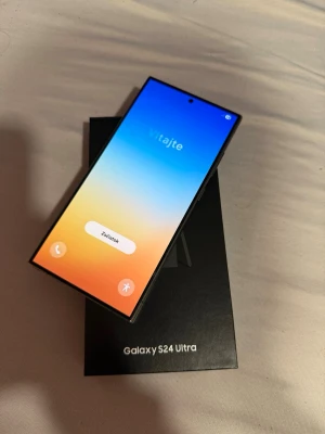 Samsung Galaxy S24 Ultra svart - Samsung Galaxy S24 Ultra i svart med stor, kantig skärm och flera bakre kameror. Telefonen har en stilren design i metall och glas, och levereras i originalkartong. Perfekt för dig som vill ha en kraftfull Android-mobil med grym kamera och modern look.