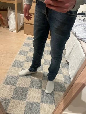 Mörkblå slim fit jeans från Nudie - W29 och L 32 Snygga mörkblå slim fit jeans från nudie med klassisk femficksdesign och lätt slitna detaljer. Jeansen har normal midja och smal passform hela vägen ner. 