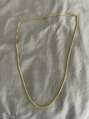 Guldfärgat tvinnat halsband - Snyggt halsband med tvinnad kedja som ger en stilren och modern look. Perfekt att bära som det är eller att kombinera med andra smycken för en personlig stil. 