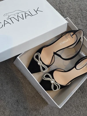 Svarta pumps med strassrosett Catwalk - Säljer min sister klackar storlek 36 Dom är oanvänd. 