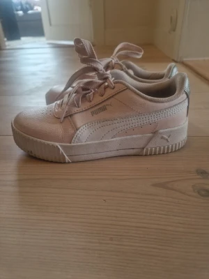 Ljus rosa sneakers från Puma - Snygga ljus rosa sneakers från Puma med klassisk logga på sidan. Skorna har lågt skaft, snörning och en robust sula. Perforering vid tårna för extra stil.