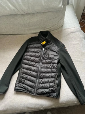 Olivgrön jacka från Parajumpers M - Snygg olivegrön dunväst från Parajumpers med quiltad framsida, släta ärmar och hög krage. Västen har dragkedja, gul detalj vid halsen och logga på axeln. Perfekt för lager-på-lager och håller dig varm under kyliga dagar. Sömmen har lostnat lite grann som man ser på sista bilden (därav billigare pris). Detta kan dock sys ihop på ett enkelt sätt!      Köpt för 3500!