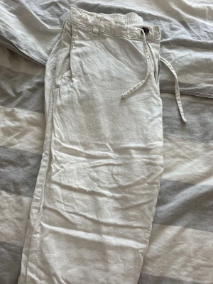 Vita linnebyxor från Selected Homme - Snygga vita linnebyxor från Selected Homme med rak passform och dragsko i midjan. Byxorna har resår i midjan, sidfickor och bälteshällor. Perfekta för en avslappnad och stilren look under varma dagar. Pris kan diskuteras vid snabb affär. Skickar samma dag eller dagen efter.
