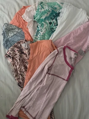 Färgglatt klädpaket med toppar för barn - Säljer ett blandat paket med toppar och linnen i olika färger och mönster, bland annat orange, rosa, vitt och grönt med bladmönster. Några plagg har spetsdetaljer och ett linne är glittrigt. Storlekarna går från 8 -11 och jag ör väldigt flexible med priset.