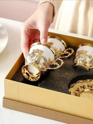 Lyxigt set med guldfärgade kaffekoppar 12 pc - Säljer ett elegant set med vita kaffekoppar i porslin med detaljer i guldmetall. Kopparna har dekorativa handtag och matchande fat med utsmyckade mönster. Perfekt för att lyfta fikastunden med en exklusiv känsla.
