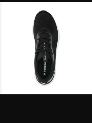 Svarta sneakers från Björn Borg - Stilrena svarta sneakers från Björn Borg med vit sula och mesh-överdel för bra andningsförmåga. Skorna har klassisk snörning och diskreta detaljer på sidan. Perfekta för en sportig och modern look.
