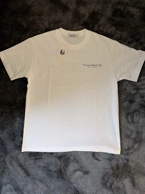 Vit Voronado Yacht Club t-shirt - Vit t-shirt från Voronado Yacht Club med tryck på bröstet och stor båtillustration samt texten 'Saint Tropez' på ryggen. Klassisk passform med rund halsringning. Perfekt för en stilren och avslappnad look.