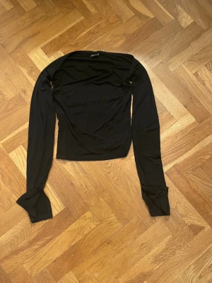 Svart långärmad topp - En svart långärmad topp med figurnära passform och enkel design. Toppen har rund halsringning och är tillverkad i ett mjukt, stretchigt material som känns bekvämt mot huden. Perfekt att styla med jeans eller kjol för en clean look.