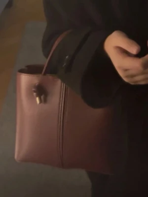 Vinröd axelväska i läderlook - Snygg mörk röd  axelväska i boxig modell med stilrena detaljer i guld. Väskan har både axelrem och handtag. Använd men inga slitage! 