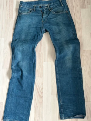 Levi's bootcut - Klassiska blå jeans från Levi's med bootcut/rak passform och fem fickor. Jeansen har en snygg tvättad look, orange sömmar och den ikoniska läderlappen bak i midjan. Tillverkade i slitstark denim, perfekta för en avslappnad och tidlös stil. Priset är inte hugget i sten. Assnygga archive bootcut jeans. W30 L32 sitter riktigt fint