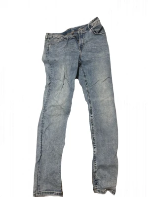 Ljusblå raka jeans - Säljer ett par ljusblå jeans med rak passform och klassisk femficksdesign. Jeansen har en något tvättad look och är tillverkade i denim. Perfekta för en avslappnad och trendig stil.