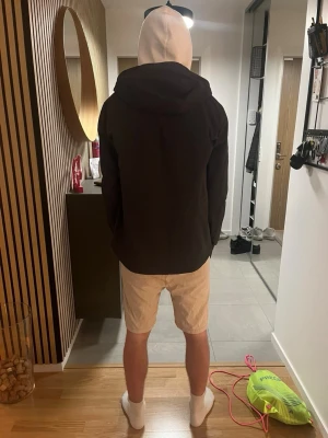 Svart vindjacka från Helly Hansen - Snygg svart vindjacka från Helly Hansen med huva och två vertikala bröstfickor med dragkedja. Jackan har en minimalistisk design och HH-logga på framsidan. Perfekt för blåsiga dagar och enkel att matcha med olika outfits. Ny pris 1200kr så hör av er vid minsta fundering. 