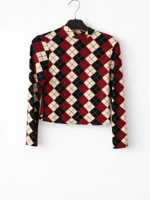 Rutig långärmad topp i beige och rött - Säljer en långärmad topp med coolt rutigt mönster i beige, rött och svart. Materialet är mjukt och stretchigt med 95% polyester och 5% spandex. Perfekt för dig som gillar retrovibes och vill sticka ut med ett unikt mönster.