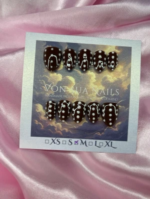 ChocoDot (M);Short Almond - Handgjorda press-on naglar i brun färg med ljusrosa prickar. Naglarna har en glansig finish och en kort mandelform. Perfekt för dig som vill ha en unik och trendig look. Levereras på snygg displaykort.M: 16 mm, 12 mm, 12,5 mm, 11,5 mm, 10 mm