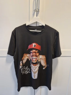 Svart t-shirt med tryck från ROMWE - Svart t-shirt från ROMWE med stort grafiskt tryck framtill som visar en person med röd keps, smycken och texten 'Active lifestyle'. Klassisk rund hals och korta ärmar. Perfekt för en streetwear-look.