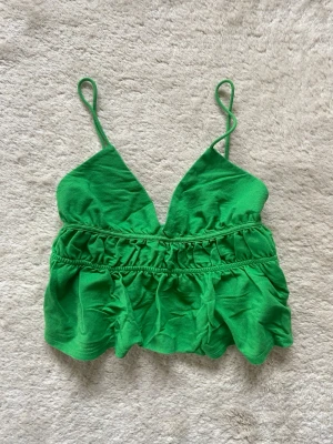 Grön topp med volang - Snygg grön linnetopp från Zara med smala axelband och v-ringning. Toppen har volangdetaljer och rynkade partier under bysten. 