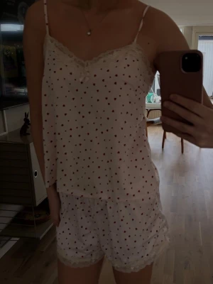 Söt pyjamas med hjärtan och spets - Ljusrosa pyjamas-set med röda hjärtan, tunna axelband och spetsdetaljer vid urringning . 