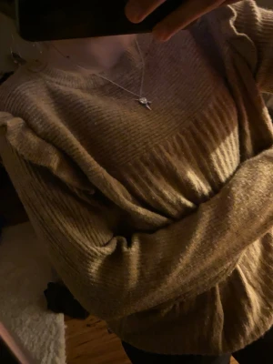 Beige ribbad tröja med volang - Säljer en beige ribbad tröja med volangdetaljer längs bröstet och axlarna. Tröjan har rund halsringning och långa ärmar. Perfekt för dig som gillar en söt och trendig stil.