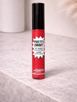 Pretty Smart rött läppglans - Snyggt rött läppglans från theBalm med glansig finish. Kommer i en smidig tub med svart lock och cool retroinspirerad etikett. Berikat med ginseng för extra vård till läpparna. Perfekt för dig som vill ha färgstarka och glansiga läppar.