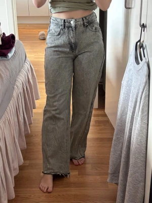 Gråa raka jeans  - Säljer ett par gråa raka jeans med hög midja. Jeansen har klassisk femficksmodell och en tvättad vintage-look. Perfekta för en avslappnad och trendig stil. 