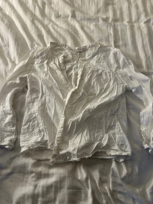 Vit långärmad skjorta från GAP - Säljer en vit långärmad skjorta från GAP i storlek M Tall. Skjortan har klassisk knappstängning framtill och är tillverkad i ett lätt bomullsmaterial. Perfekt för att ha på stranden över bikini och baddräkt. Har en fläck på ena ärmen som ej går bort