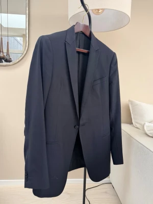 Kavaj från Armani’s modevisning - Armani Collezioni kavaj – svart  Säljer en stilren kavaj från Armani Collezioni som kommer från en modevisning. Klassisk svart färg som fungerar både till kostymbyxor, chinos eller jeans. Tidlös modell med enkelknäppning och smal silhuett. En mindre reva på ena ärmen, som självklart kan åtgärdas (se bild), annars mycket fin.