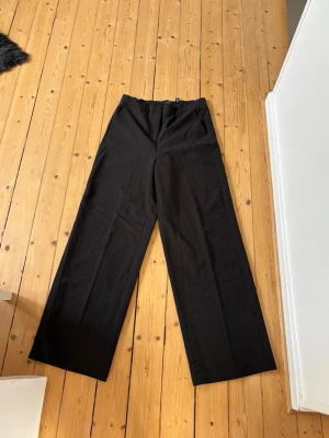 Vida svarta kostymbyxor Vero Moda - Säljer ett par svarta kostymbyxor från Vero Moda med hög midja och vida ben. Inga fickor bak.Aldig använt. Längd 32