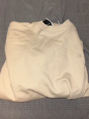 Beige sweatshirt från Axel Arigato - Säljer en stilren beige sweatshirt från Axel Arigato med diskret broderad logga på bröstet. Tröjan har rund halsringning, ribbade muddar och är tillverkad i mjukt bomullsmaterial. Perfekt för en clean och avslappnad look. Ordinarie pris 1949 kr. Kontakta mig för pris.