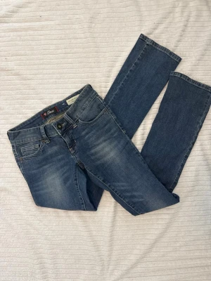 Lågmidjade blå guess  jeans  - Snygga lågmidjadeblå jeans från Guess.            Storlek 25 passar XS.                                              Jeansen har låg midja och är tillverkade i stretchigt denim för en bekväm passform.