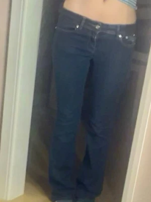 Mörkblå bootcut jeans med detaljer - Säljer ett par mörkblå bootcut jeans med låg midja och snygga fickdetaljer bak med nitar och sömmar. Köpa nya 600kr, knappast använda.