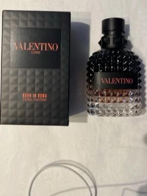 Valentino Uomo Born In Roma Coral Fantasy - Valentino Uomo Born In Roma Coral Fantasy är en parfym för män med en lyxig, mörk glasflaska som har nitar och en gradient från svart till klar. Förpackningen är svart med orange text och har en modern, edgy design. Flaskan rymmer 50 ml och är perfekt för dig som gillar exklusiva dofter.