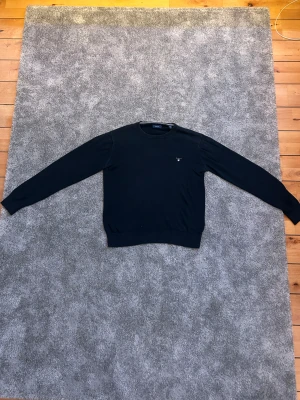 GANT Tröja - Säljer denna schyssta GANT tröjan för ett bra pris. Marinblå tröja med modern look. Använd en del och lätt sliten men behåller fortfarande kvalitet. Storlek är 176 cm och rekommenderad för 16 års ålder. Vid fler frågor eller funderingar så är det bara att kontakta!                  Mvh // JJ Studios