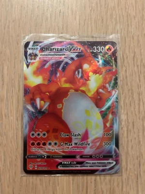 Charizard VMAX 020/189 – Pokémonkort - Säljer ett Charizard VMAX samlarkort från Pokémon TCG med färgstark holografisk design. Kortet har 330 HP och attacker som Claw Slash och G-Max Wildfire. Perfekt för dig som gillar att samla eller spela Pokémonkort. Kortet är i bra skick och fraktas säkert med en plastficka och annat runt. 