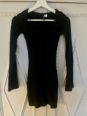 Svart ribbad kortklänning Gina Tricot - Snygg svart ribbad kortklänning från Gina Tricot med lång ärm och rundad urringning. 