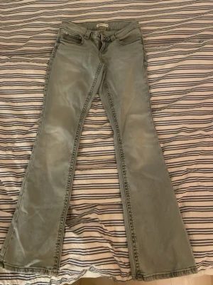 Ljusblå bootcut jeans från Gina Tricot - Säljer ett par ljusblå bootcut jeans från Gina Tricot. Jeansen har klassisk femficksdesign med en extra ficka med lock och knapp bak. Tillverkade i mjukt denimtyg och har utsvängda ben för en retrovibe.