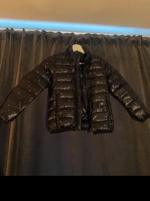 Marinblå dunjacka med rosa prickar barn kläder strl 116 - Snygg marinblå dunjacka med rosa prickar och quiltad design. Jackan har hög krage, dragkedja framtill och medföljande förvaringspåse i samma mönster. Perfekt för kalla vinterdagar och lätt att packa ner.