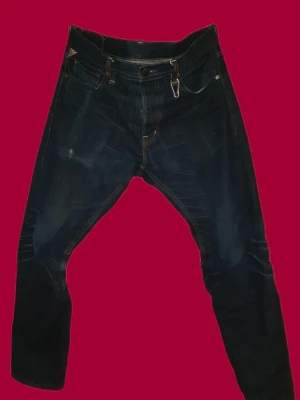 Ralph Lauren jeans - Säljer ett par mörkblå jeans från Denim & Supply Ralph Lauren. Klassisk femficksmodell med snygga kontrastsömmar och en liten detalj med amerikansk flagga vid fickan. Jeansen har rak passform och är tillverkade i slitstarkt bomullsdenim.