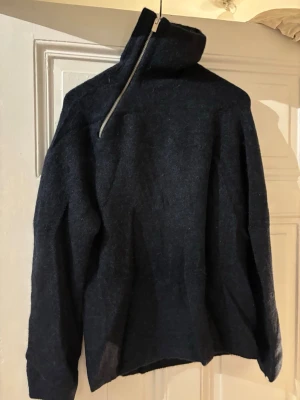 Mörkblå stickad tröja med dragkedja - Säljer en mörkblå stickad tröja med hög krage och sned dragkedja. Aldrig använd.
